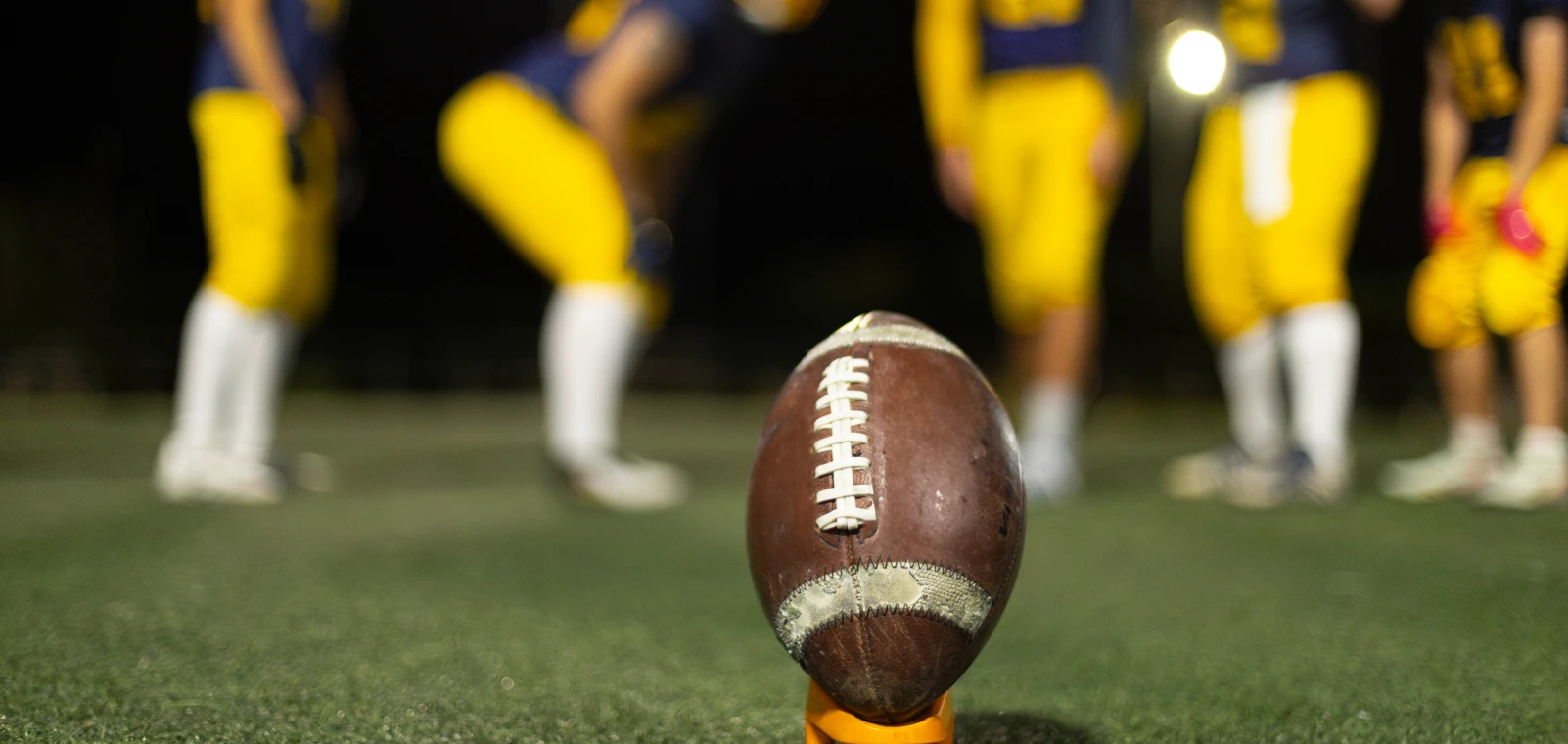 Football on tee with players in background
