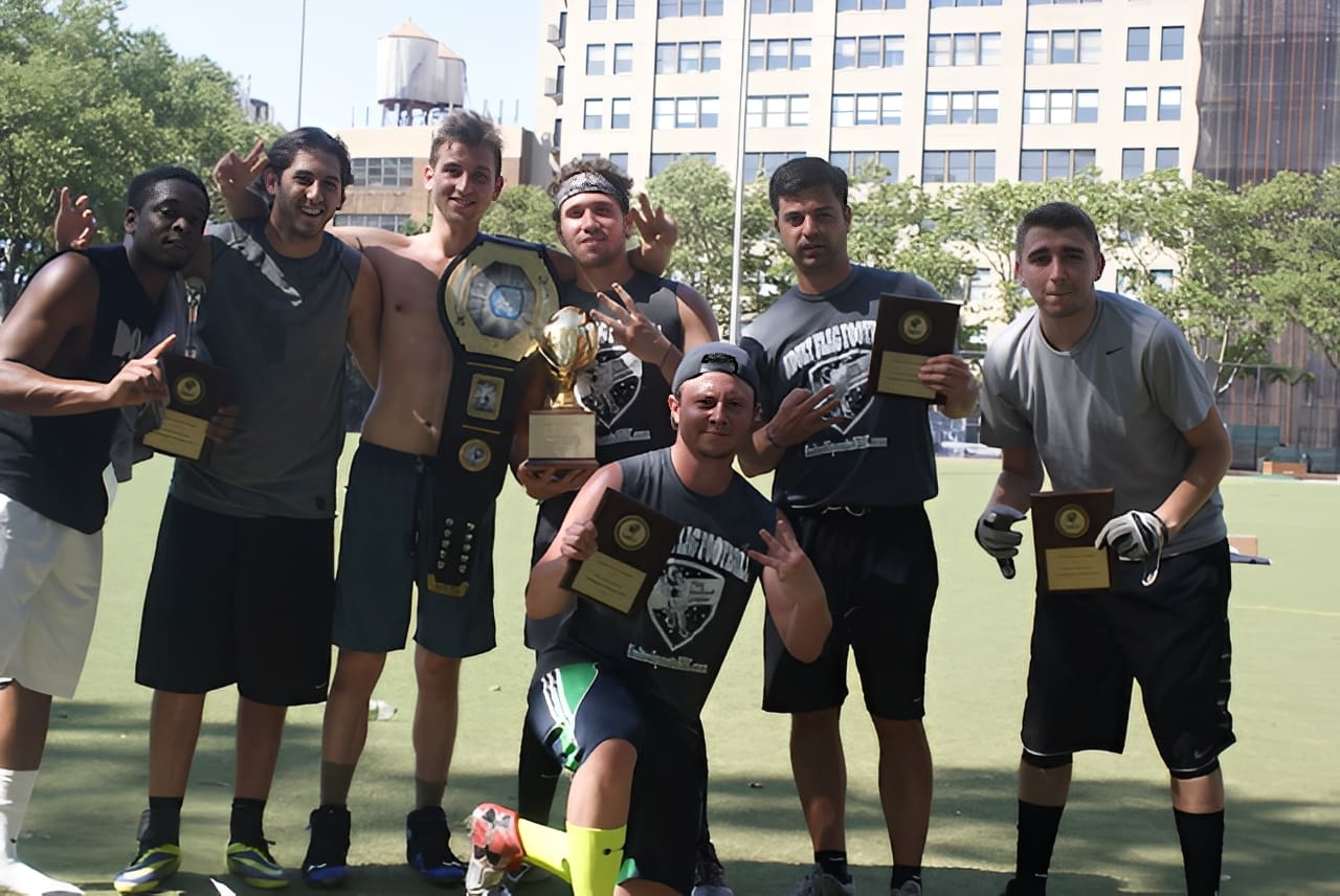Friends holding sports trophies on field