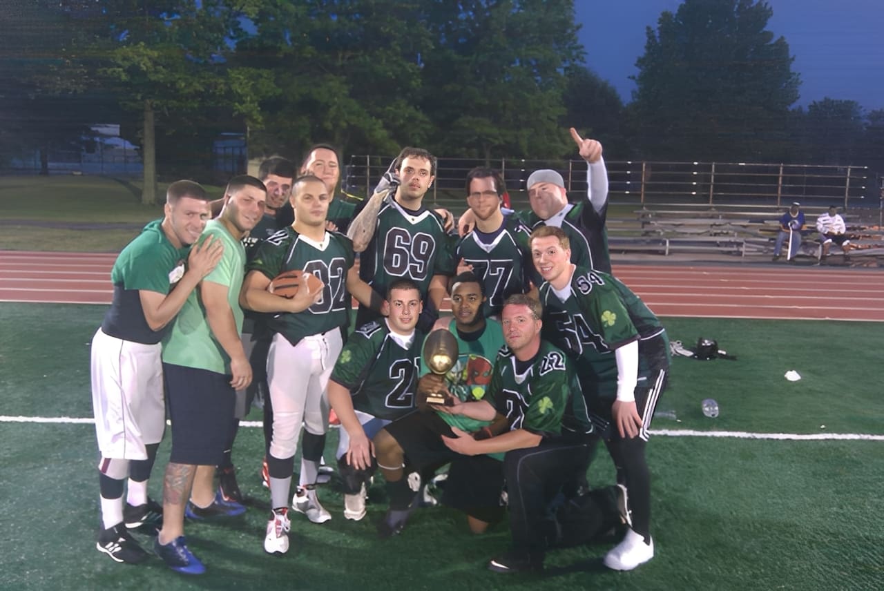 Football team celebrating with trophy on field.
