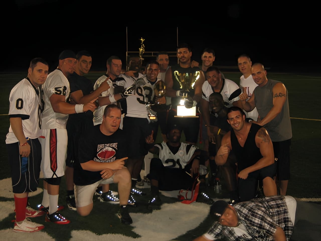 Football team celebrating with trophy at night.